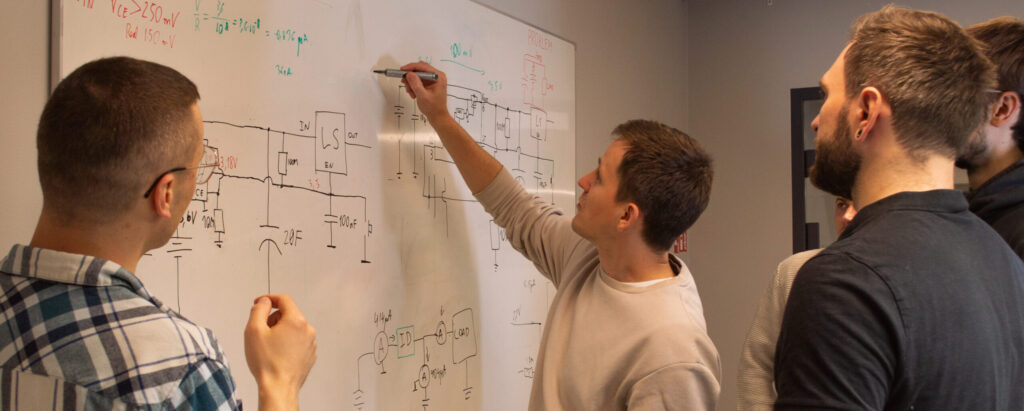 LMT IoT team collaborating on an electronic circuit diagram during IoT solution development.