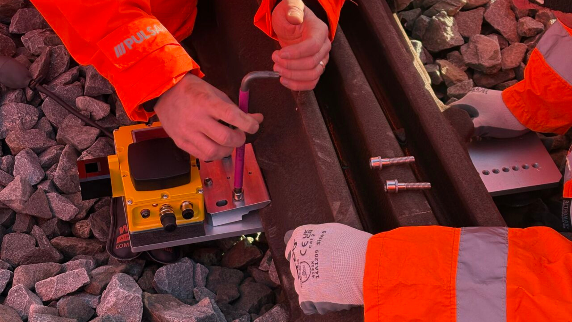 Railway workers attaching a RailSense monitoring sensor to a rail.